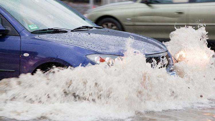 Car driving through a flooded street 和 possibly having flood damage as a result.